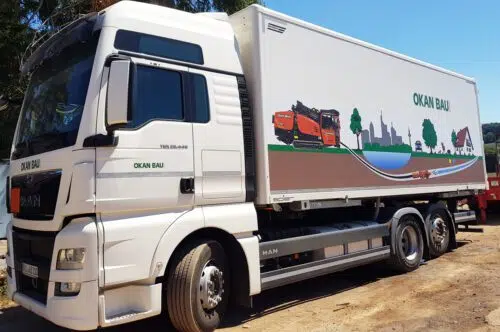 Weißer MAN LKW mit Großformat-Digitaldruck und Schriftzug Okan Bau auf dem Kofferaufbau