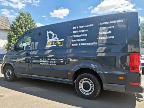 Dunkelgrauer Kastenwagen mit Fahrzeugbeschriftung und Leistungsübersicht der MS-Tiefbau GmbH