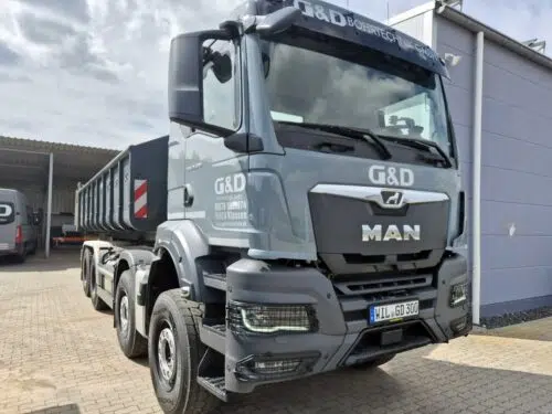 Grauer MAN Abrollkipper mit Logo und LKW-Beschriftung von G&D Bohrtechnik