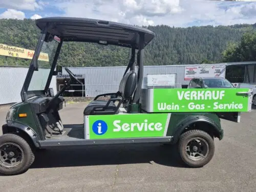 Kleines Elektrofahrzeug mit grüner Beschriftung Verkauf Wein, Gas und Service