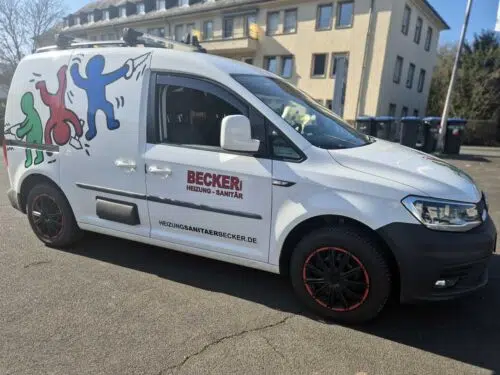 Weißer VW Caddy mit bunter Figurengrafik und Beschriftung Becker Heizung-Sanitär